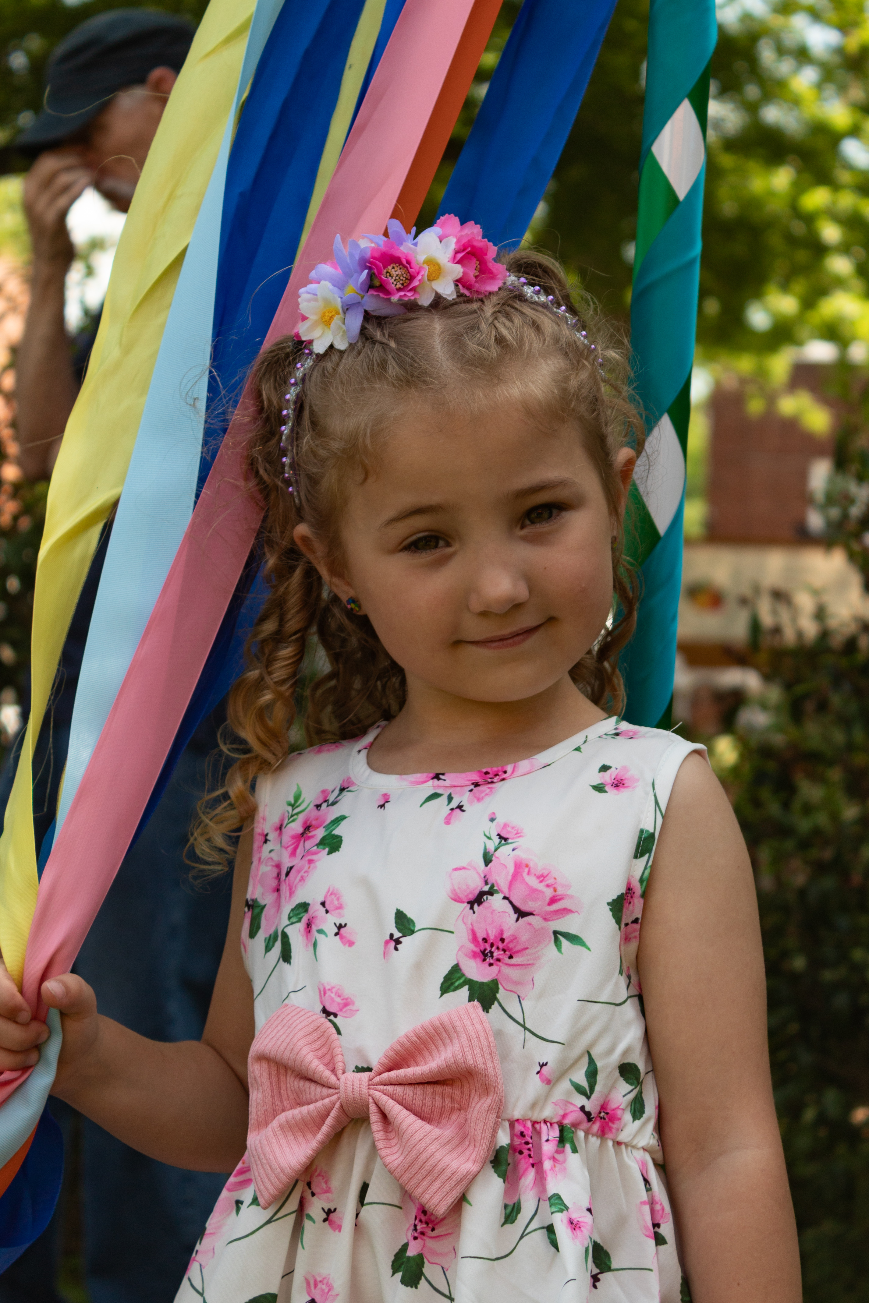 Young child standing among colorful May pole ribbons