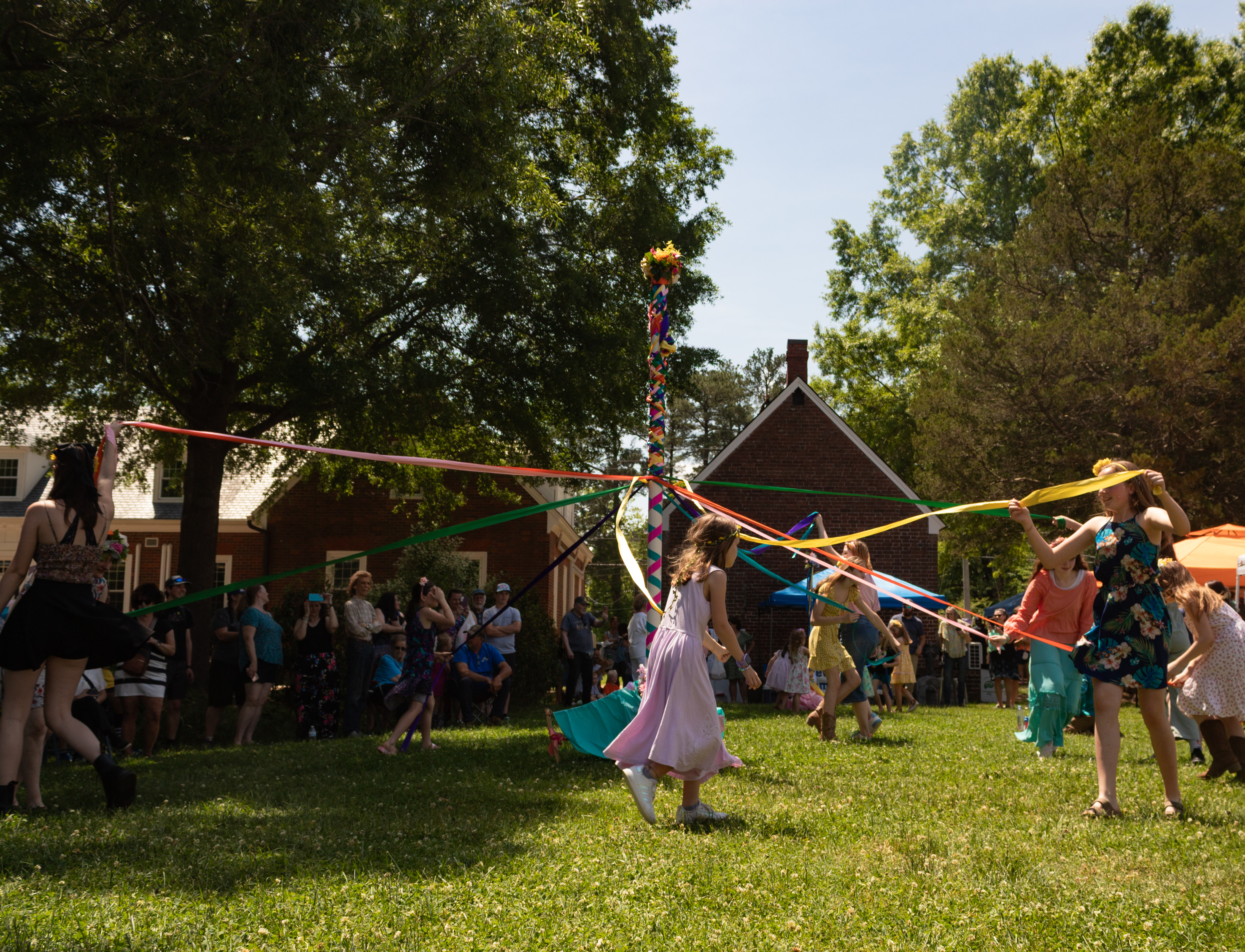 Children and teens dancing around the May pole on the Court Green