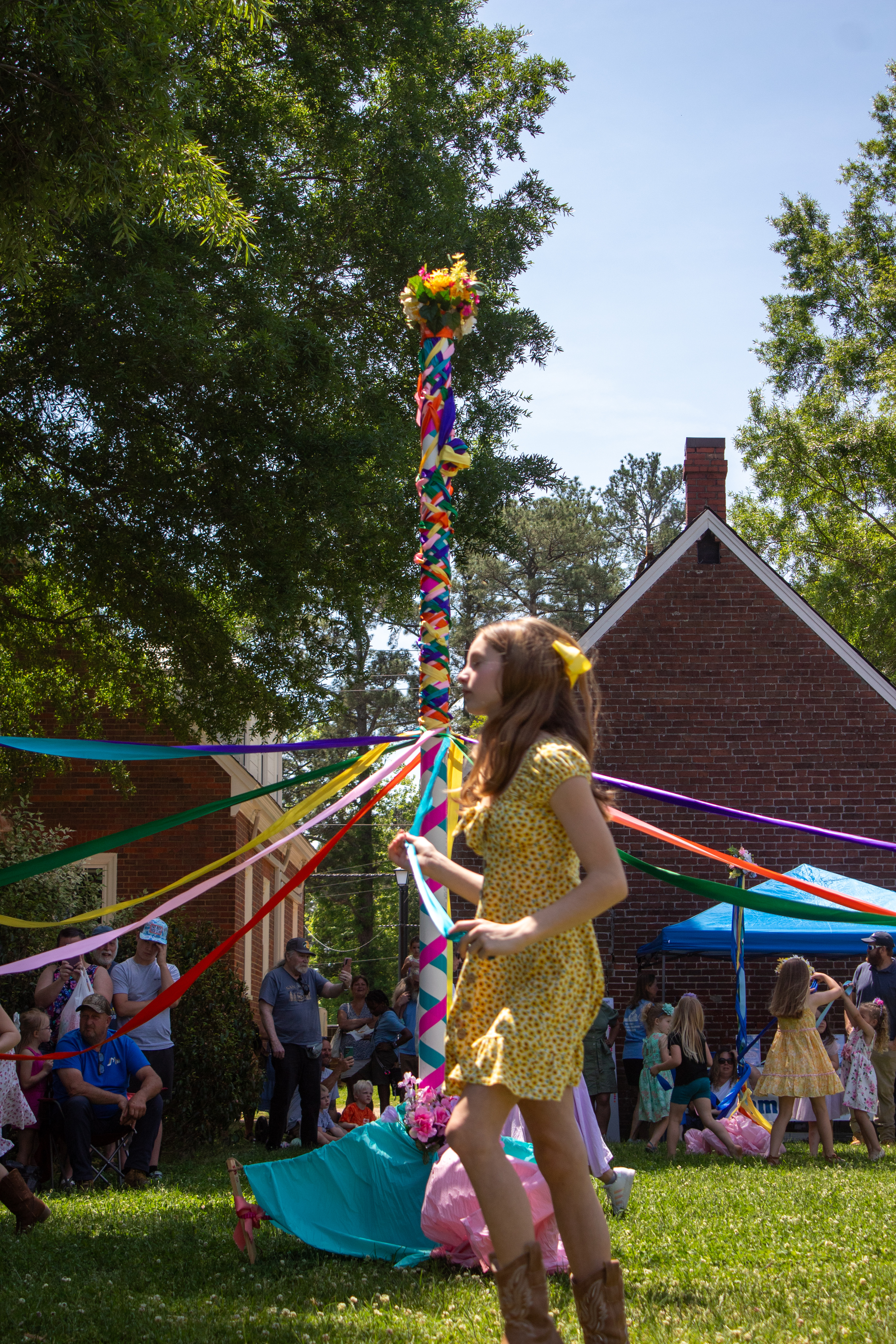 Colorful May pole with ribbons and brick buildings in the background